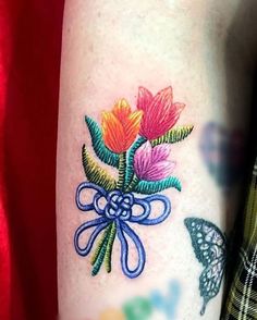 a woman with a tattoo on her arm has a bouquet of flowers and butterflies in it