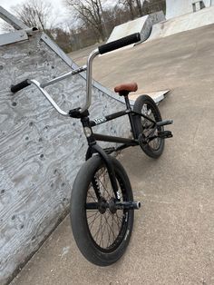 a black and silver bike parked on the side of a skateboard ramp in front of a wooden wall