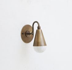 a wall mounted light on the side of a white wall with a brown handle and bulb