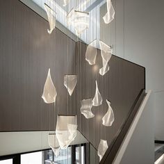 an artistic chandelier hanging from the side of a staircase in a modern building