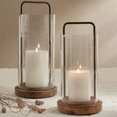 two white candles are sitting in glass containers