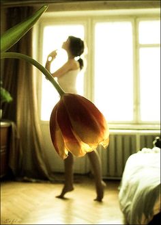 a woman standing in front of a window with a flower on it's back