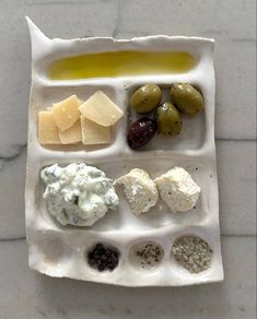 a tray with different types of cheese and olives