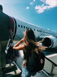 a woman walking up the stairs to an airplane with her hair blowing in the wind