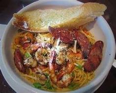 a bowl filled with pasta and shrimp next to a slice of bread