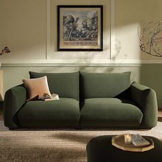 a living room with a green couch, coffee table and painting hanging on the wall