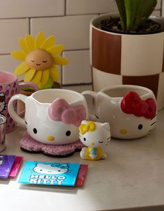 hello kitty mugs and other items on a counter top next to a potted plant