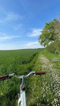 a bike is parked on the side of a dirt road in front of a field