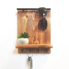 a wooden shelf with sunglasses and a potted plant on it, hanging from the wall