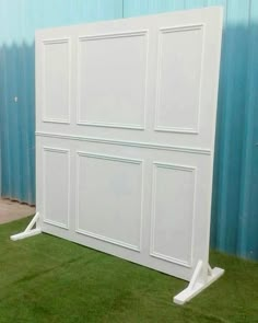 a large white bed frame sitting on top of a green grass covered floor next to a blue wall