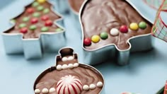 some kind of chocolate christmas tree cookie cutters on a blue table with candy and candies