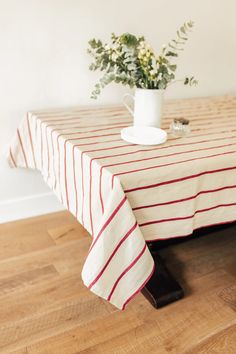 a table with a red and white striped cloth on it, next to a plant