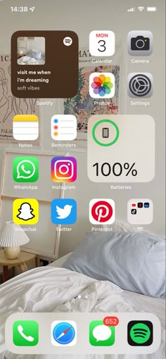 an iphone screen with various icons on it and a bed in the foreground,