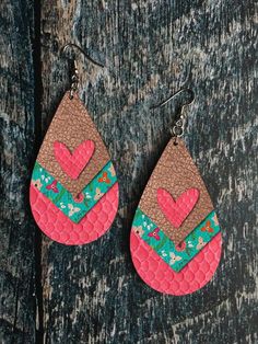 the pink and green leather earrings are decorated with heart shaped shapes, on a black background