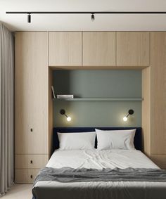 a bed with white sheets and pillows in a room that has wooden cabinets on the wall