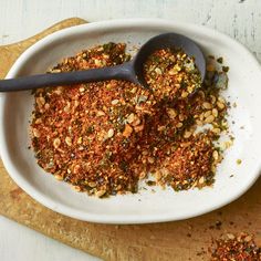 a white bowl filled with spices on top of a wooden cutting board next to a spoon