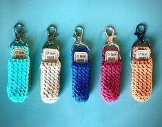 four crocheted key fobs are lined up on a blue surface, each with a name tag