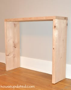 a wooden bench sitting on top of a hard wood floor next to a white wall