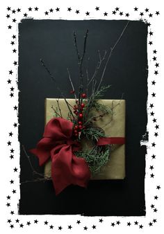 a present wrapped in brown paper with a red bow and berries tied to the top