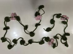 several crocheted flowers are arranged on a white counter top, with one pink flower in the center