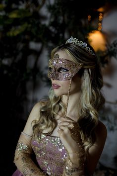 a woman wearing a masquerade and holding her hand up to her face in the dark