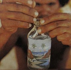 a person holding a bottle with palm trees on it