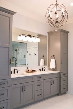 a large bathroom with double sinks and gray cabinets