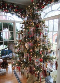 a decorated christmas tree in the middle of a living room with lots of ornaments on it