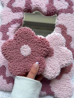 a person holding up a pink and white knitted teddy bear shaped door hanger