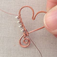 someone is making a heart shaped wire decoration