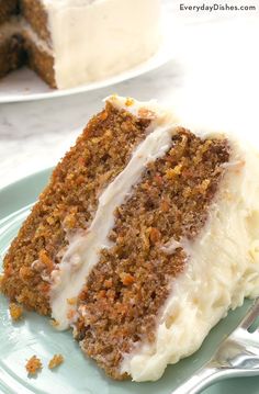 a slice of carrot cake with white frosting on a plate next to a fork