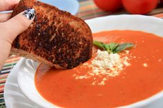 a person dipping some bread into a bowl of tomato soup