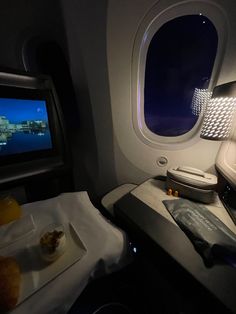 an airplane seat with food on it and a tv in the back ground next to it