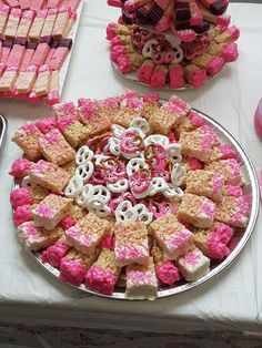 pink and white desserts are arranged on a silver platter, along with other sweets