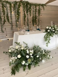 flowers and greenery are arranged on the table