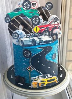 a cake with cars on it sitting in front of a window