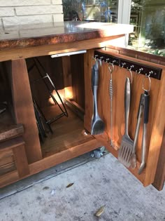 an open cabinet with utensils hanging from it's sides and on the inside