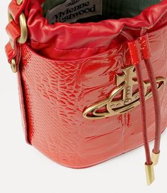 Our Daisy Drawstring Bucket bag receives a croc-embossed motif, complete with a drawstring closure. The interior 'Moire' lining recalls the 18th century wall coverings at the Wallace collection, while the line orb plaque on the front panel alludes to Vivienne's vision for taking tradition into the future. Red Vivienne Westwood, Wallace Collection, Drawstring Bucket Bag, Into The Future, Mens Jewelry Bracelet, Lace Boots, Vivienne Westwood, Lace Up Shoes, The Line