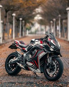 a red and white motorcycle parked on the side of a road next to some trees