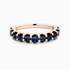 an 18k rose gold band with blue sapphires on the sides, set against a white background