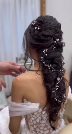 a woman is getting her hair done in a bridal gown with flowers on it