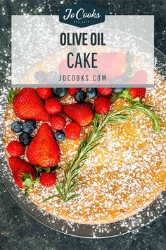 a cake with strawberries and blueberries on top, topped with powdered sugar