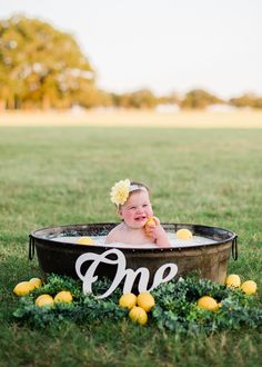 a baby sitting in a tub with the word one on it and lemons around it