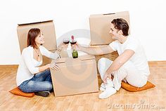 a man and woman sitting on the floor with boxes holding wine glasses in their hands