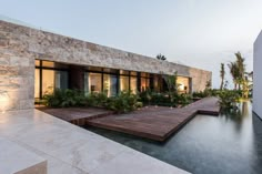 a house that is next to a body of water with plants growing on the outside