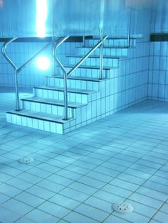 an empty swimming pool with stairs and tiled floors