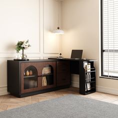 a desk with a laptop on top of it in front of a window and a rug