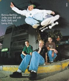 a skateboarder is doing a trick in the air while two other men watch