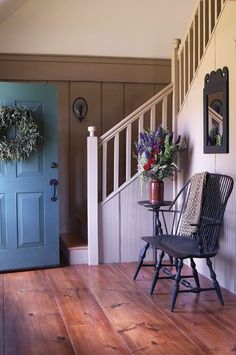 a blue door sitting next to a wooden floor in front of a stair case with wreaths on it