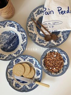 three blue and white plates with cookies, crackers and spoons on them next to a tea towel